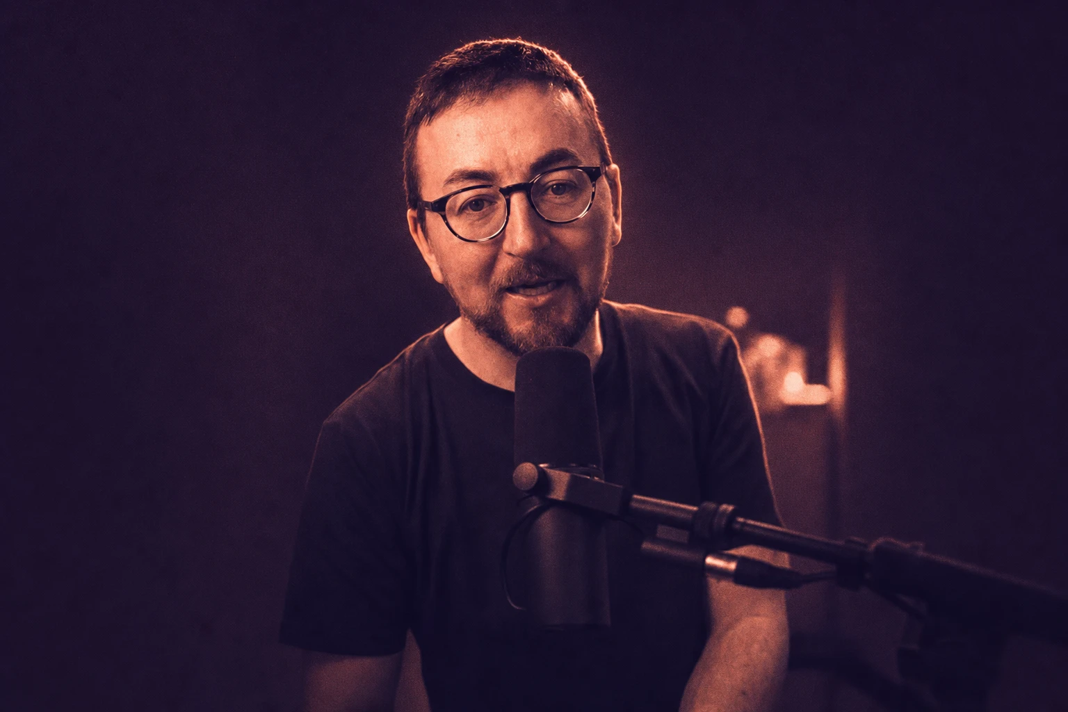 Coral and aubergine portrait of Gareth speaking into a microphone