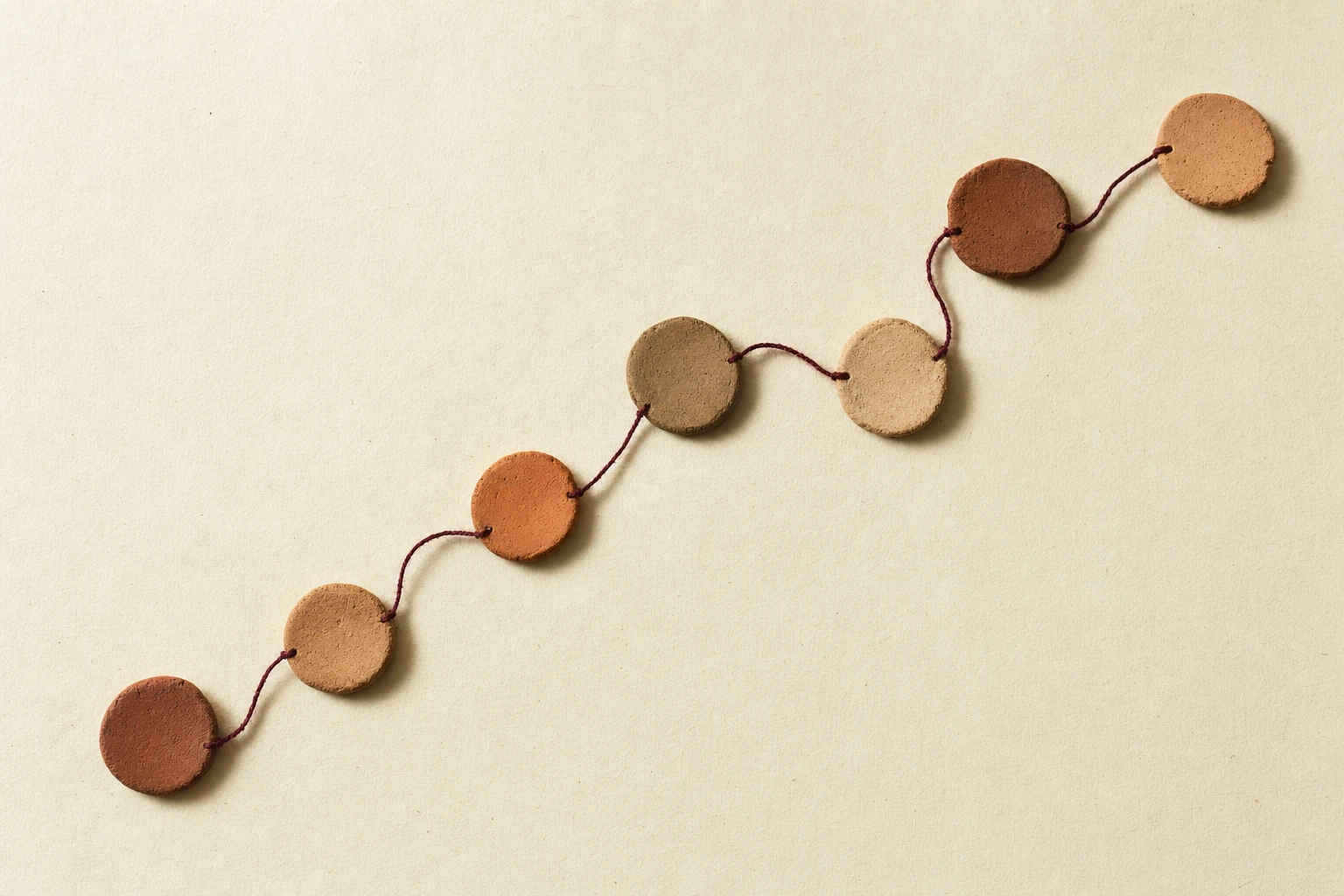 Seven handmade clay markers joined by a burgundy thread: an illustration of the seven career chapters below.